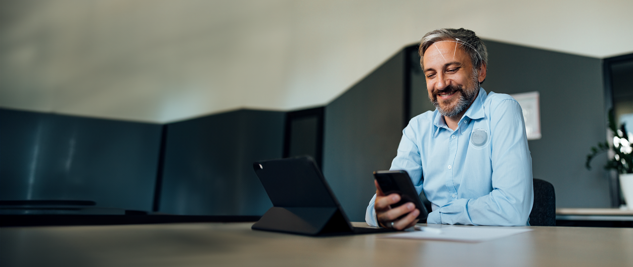 älterer Mann kann aufgrund von Tiefer Hirnstimulation wieder unbeschwert den Alltag mit Handy und Tablet meistern